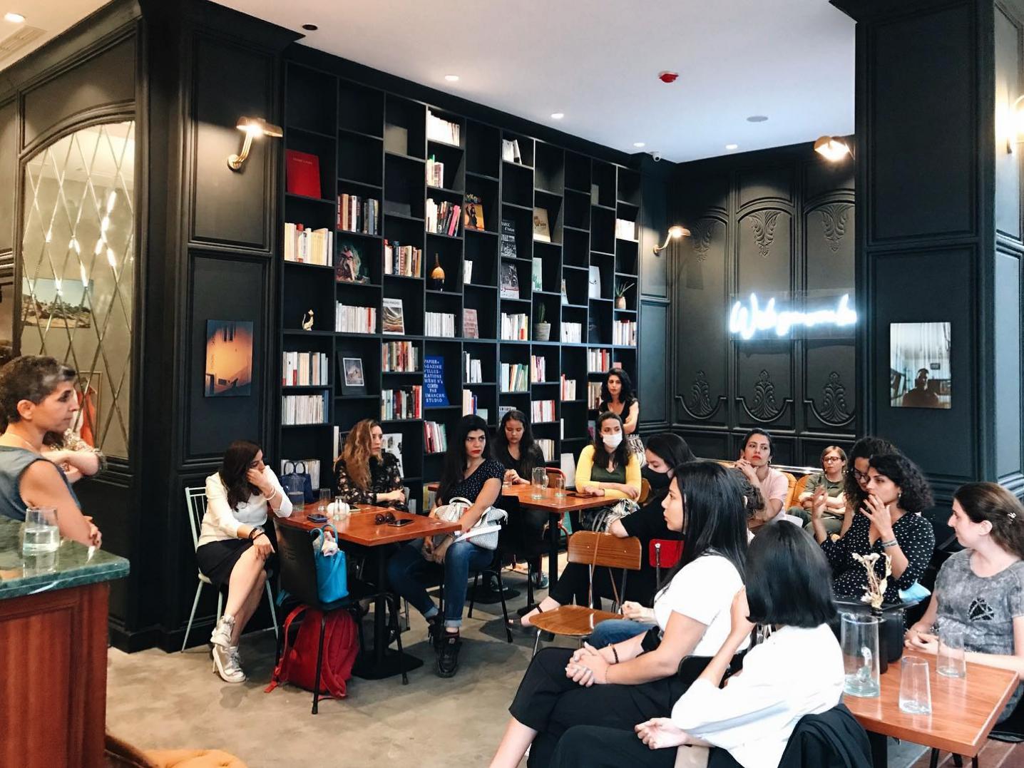 a café full of people sitting at tables with bookshelves in the background