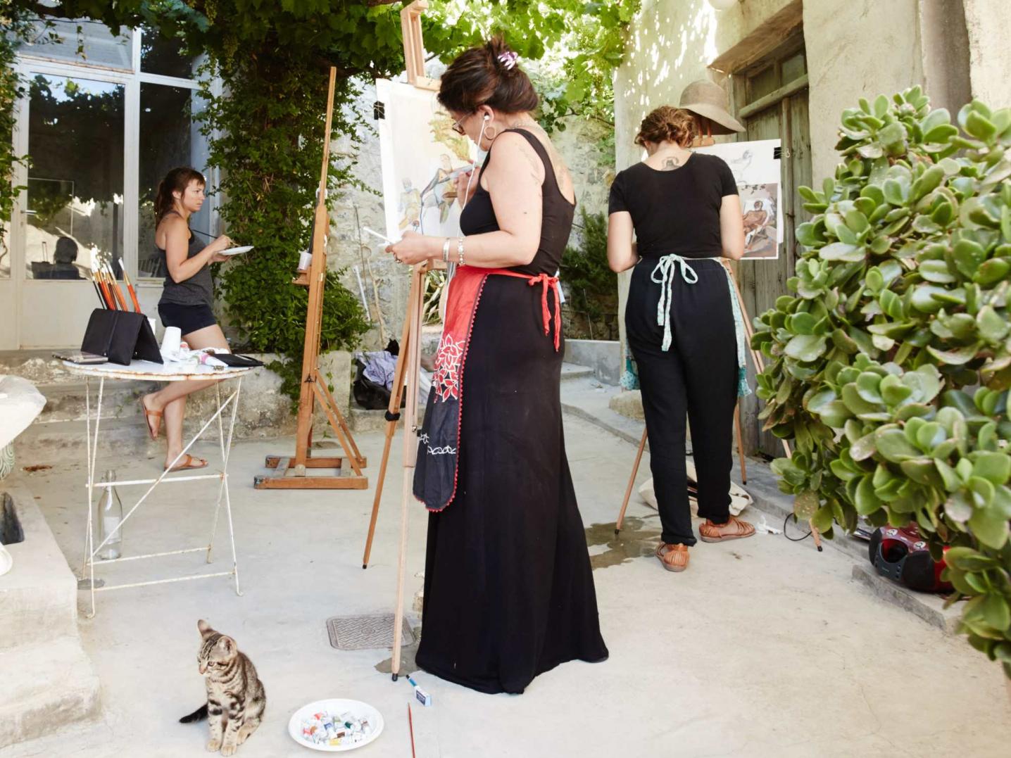 three women artists painting on easles outside an old village house in Crete, Greece