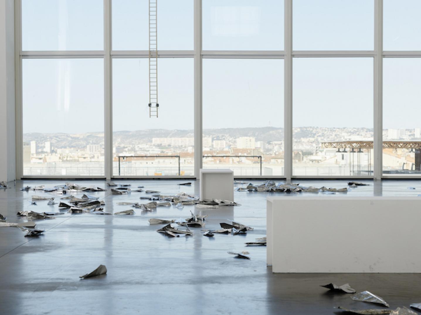 a vast space with large windows looking out over the city, with works of art on the floor