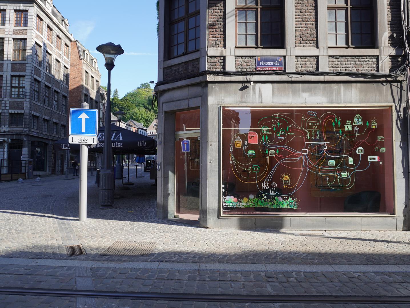 A street in Liège including an empty shop with art on the window.