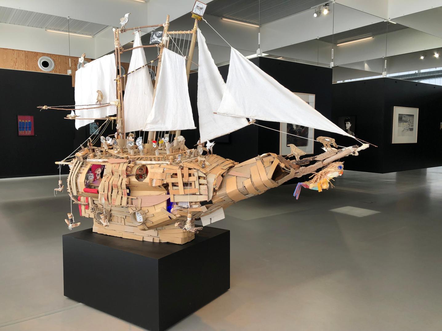 An art piece in form of an ark (boat) displaying drawings, paintings and sculptures, and made of paper, cardboard and objects.