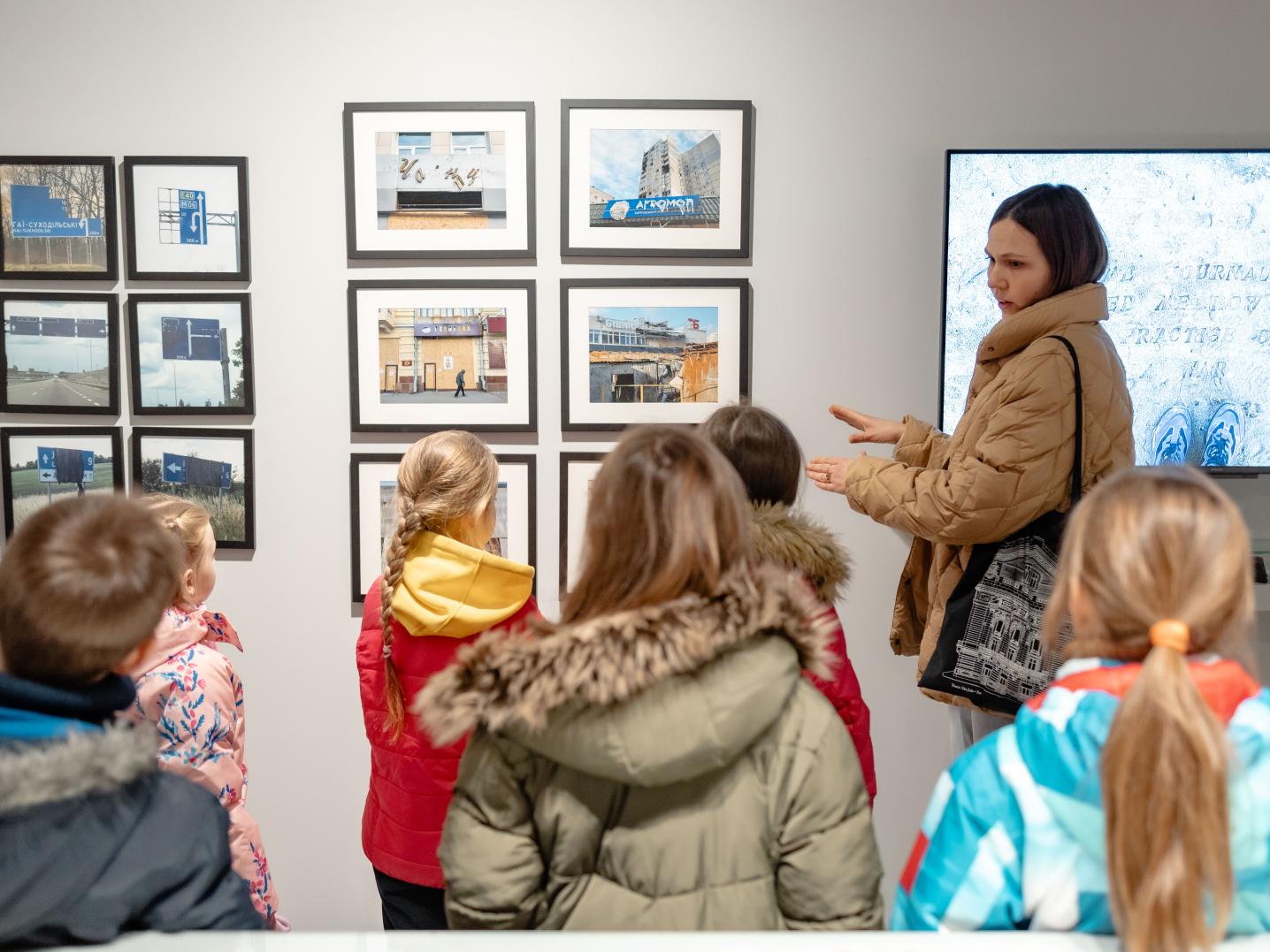 An adult guide showing artworks to children in a gallery