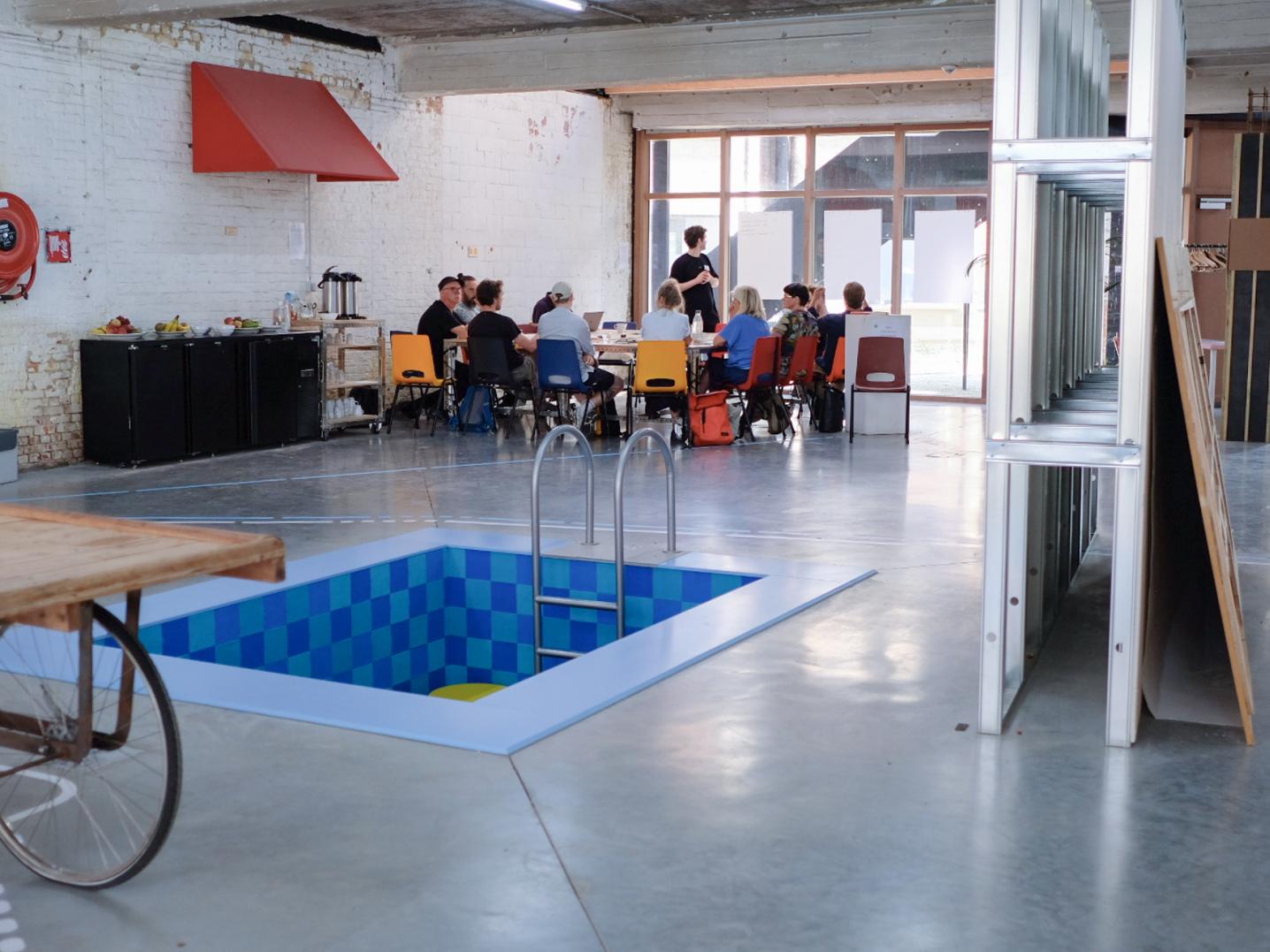 Cultural space with an empy pool and people sitting around a table