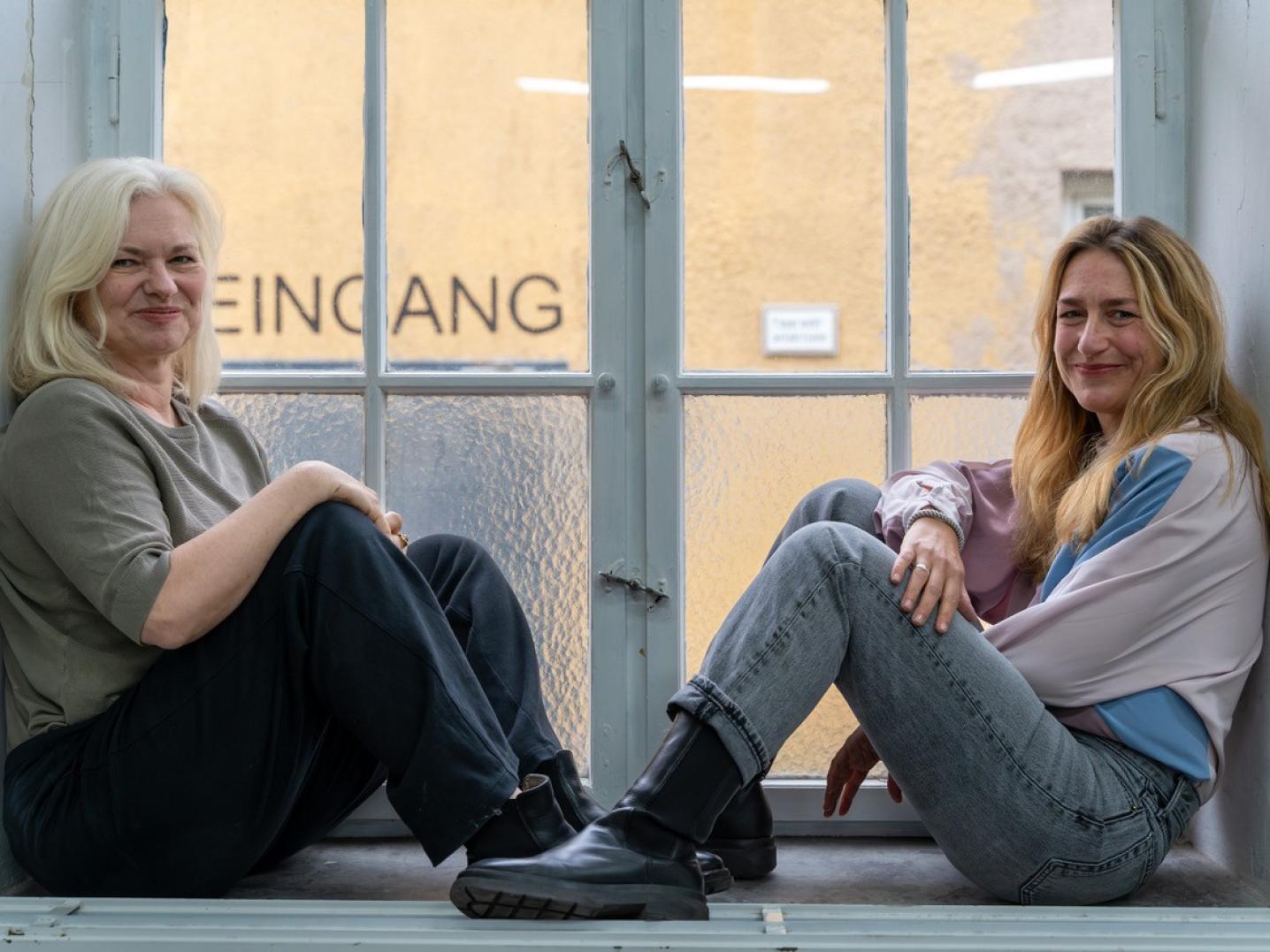 Two women working for the Tanzbüro sitting in front of a window