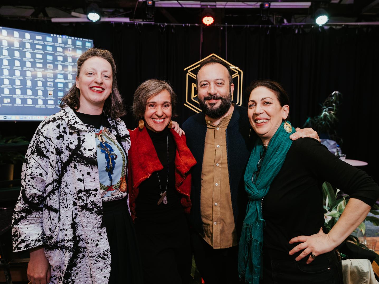 four people posing in front of a screen