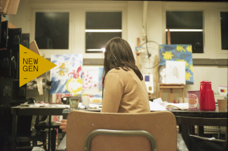 Girl sitting in front of table with paintings