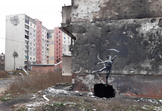 a graffiti on a shelled building in Irpin, Ukraine, of a woman in a leotard and a neck brace waving a ribbon