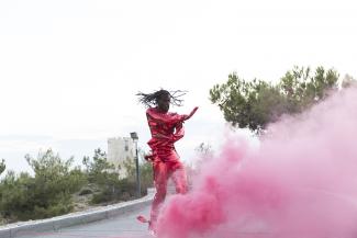 a male dancer in a pink sequin suit with pink smoke