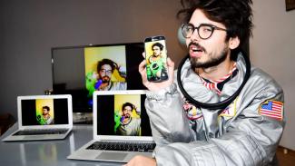 Cesar Majorana with several laptop screens and an phone