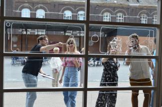 Four comic artists paint a window at a school in Charleroi