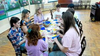 A group of children sitting around a table weaving bracelets in yellow and blue