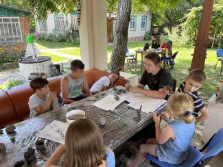 group of young people claying at a table in a garden