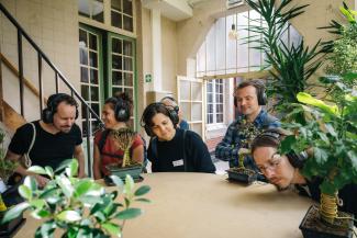 People sitting at a table with headphones on listening to the sound of plants.