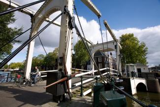 view on an old amsterdam drawbridge and canal, and a woman cycling