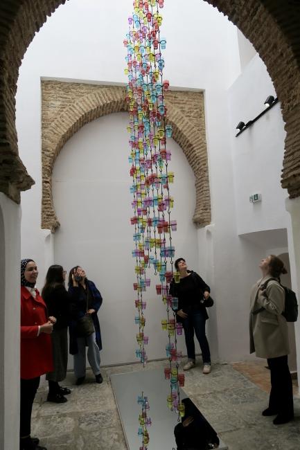 people watching a work of art with glass objects hanging from the ceiling in the Kasbah modern arts space in Tanger