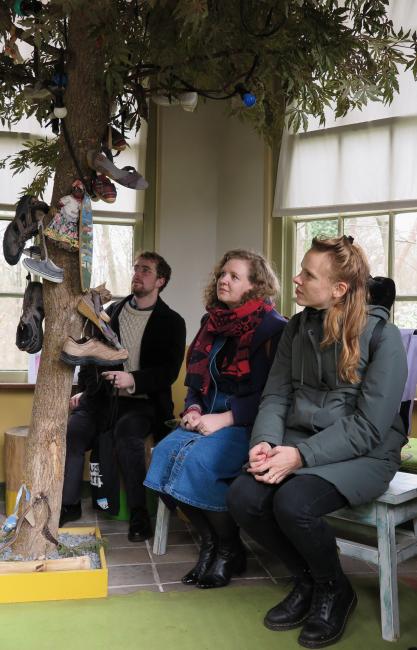 three people sitting around a tree with shoes laced to it