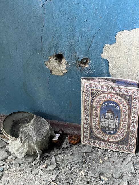 In front of a turquoise wall sits a book with a picture of the Orthodox Cathedral of Christ the Saviour in Moscow on the cover, in a sea of shattered glass