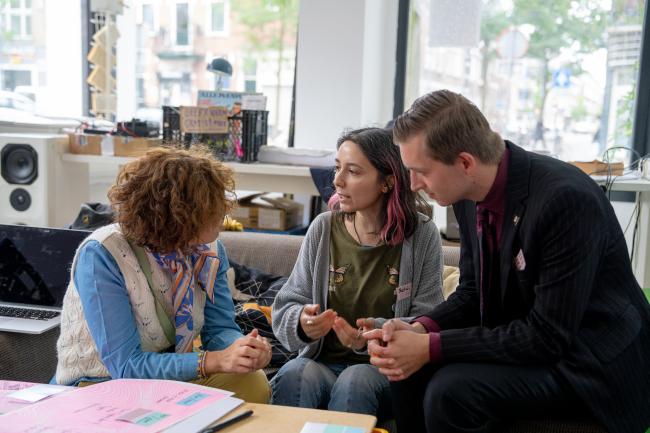 Three people sitting around a table talking