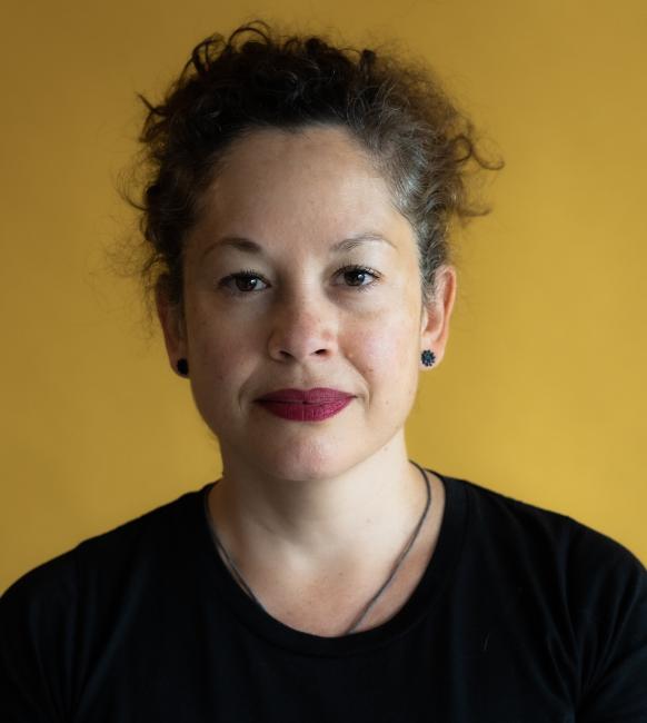 Patricia Werneck Ribas wearing a black shirt posing in front of a yellow wall