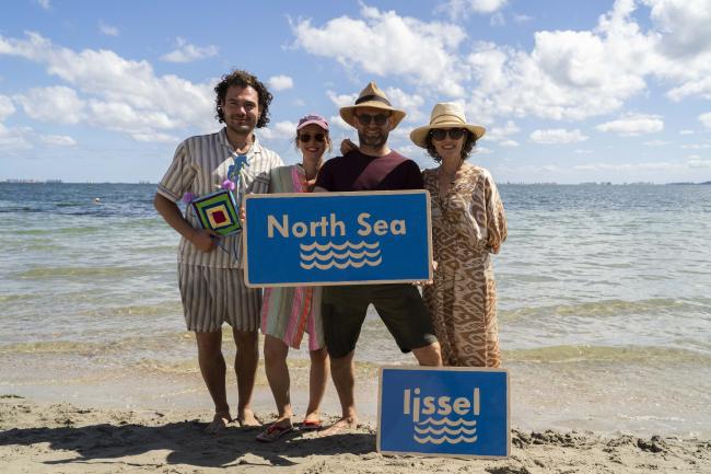 A group of people standing on a beach holding a sign saying "North Sea"