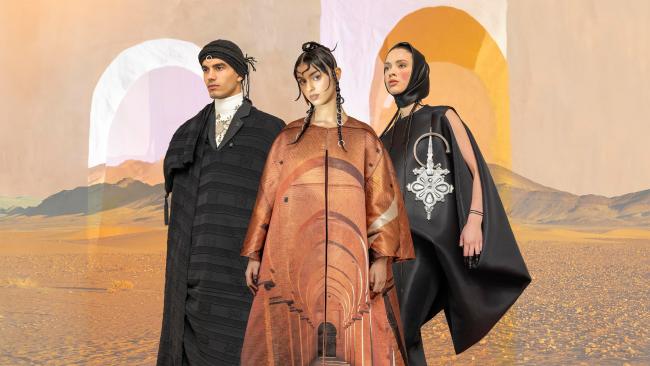 Three Moroccan models wearing flamboyant Moroccan fashion with a desert background
