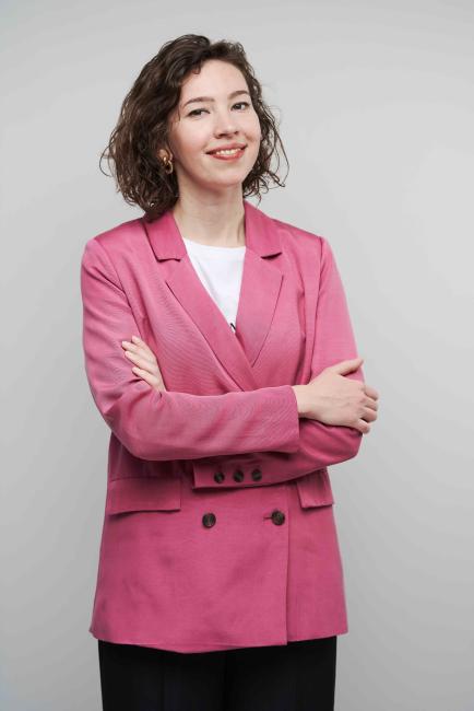 A woman posing against a grey wall