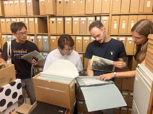 four people gathered in an archive looking at old photos and documents