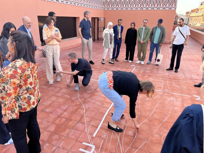 a group of people writing with chalk on the floor of a roof top