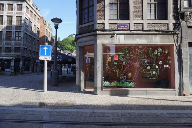 A street in Liège including an empty shop with art on the window.