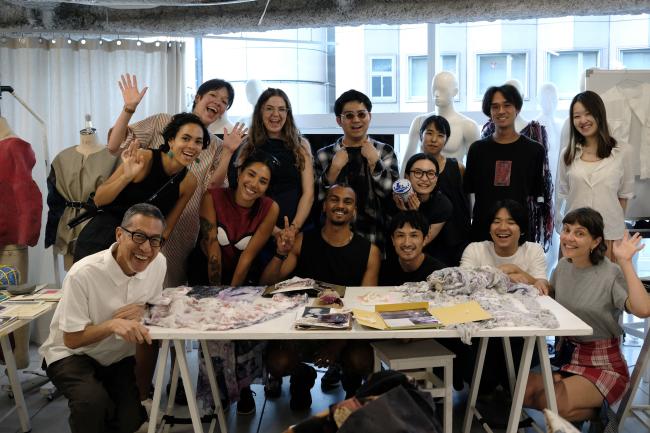 a group of people sitting and standing around a table cheering to the photographer