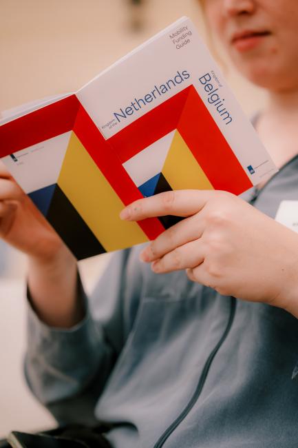 Person holding a little booklet with the title Funding Guide the Netherlands and Belgium