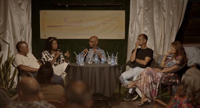  a group of people sitting around a table talking in front of an audience