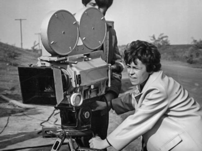 Kira Muratova operating a vintage film camera with dual reels on set, focused at work