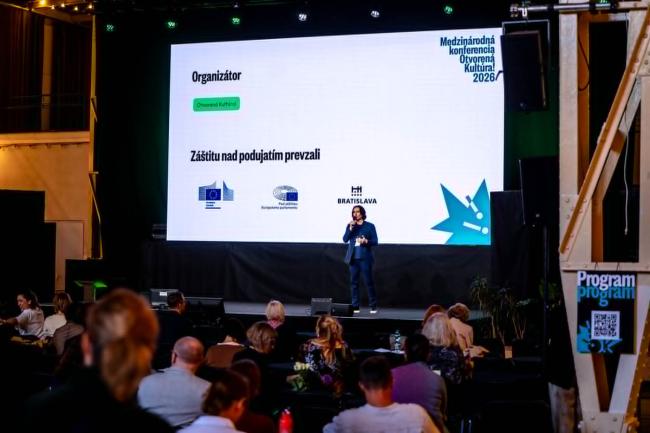 Person speaking at a podium in front of a big audience, in a theatre style venue.