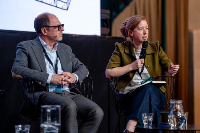 Panel discussion with two speakers seated on a stage