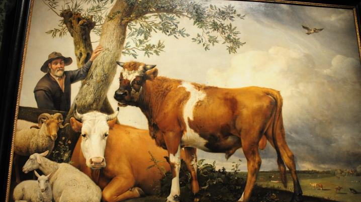 Painting of a man standing by a tree with a bull, a cow and several sheep.