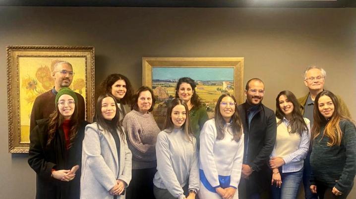 a group of people standing in front of a wall with paintings by Van Gogh