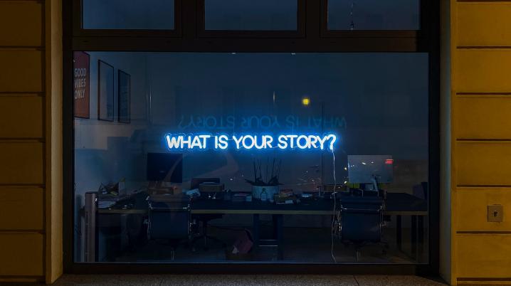 a window with a neon sign reading what's your story