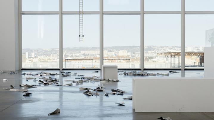 a vast space with large windows looking out over the city, with works of art on the floor