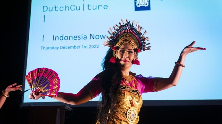 An indonesian traditional dancer on a stage with a screen behind mentioning DutchCulture Indonesia Now 2022