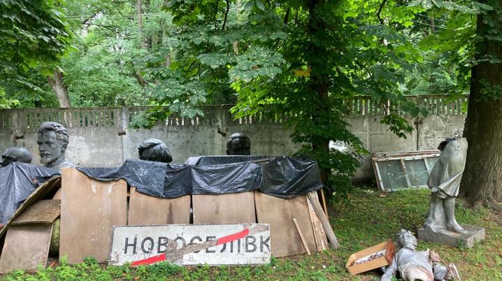 A garden filled with road signs in Ukrainian and broken statues.
