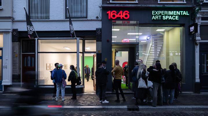 Groups of people standing on the pavement in front of an art space