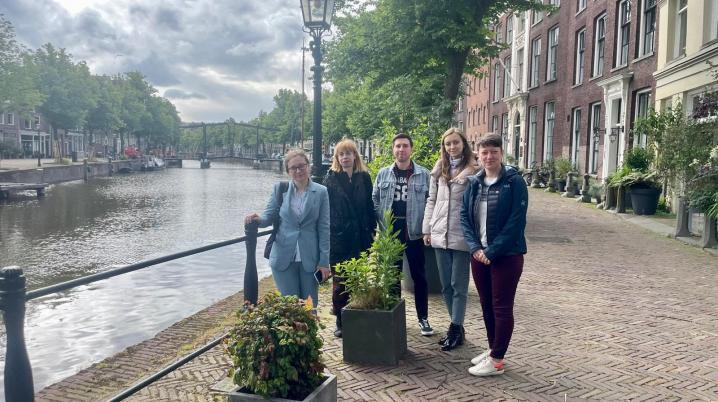 five people posing for the camera next to a dutch canal
