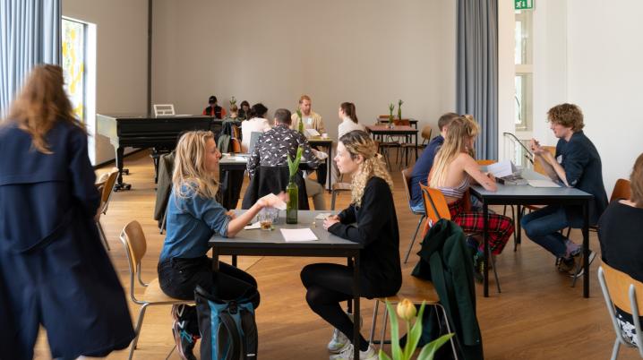 two people in conversation around a black table in a sunny room at the Jan van Eyck Academy