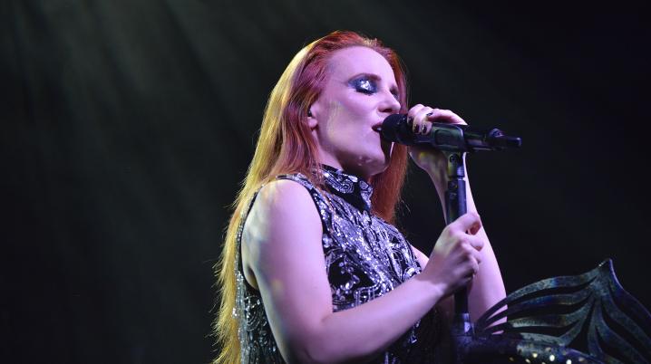 A woman with long red hair singing on stage