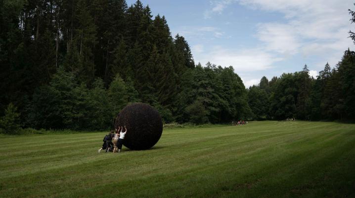 Forest and a couple of people pushing a black ball