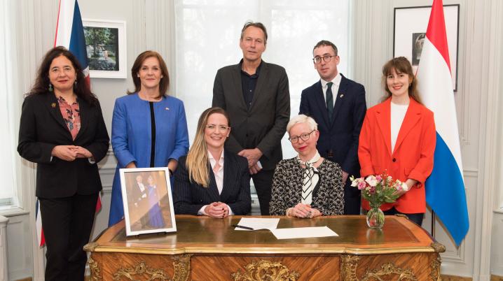 7 people from DutchCulture, British Council and the Dutch government sit around a table where the memorandum is signed.