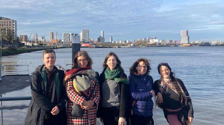Five women standing in front of the skyline of Rotterdam and the Maas river.