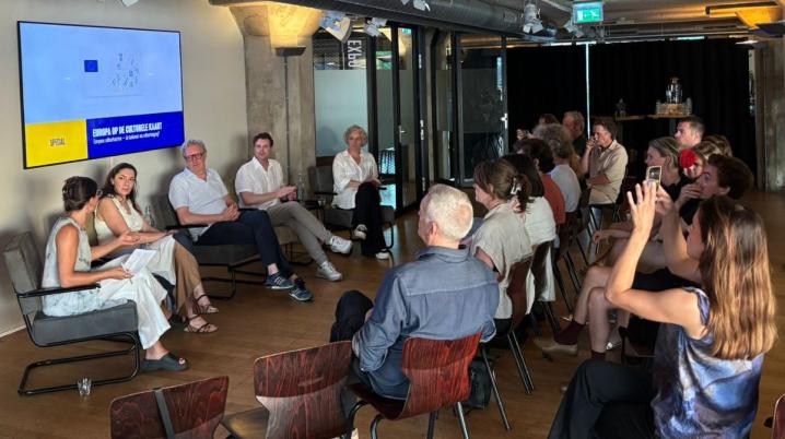 group of five people in a panel discussion in front of an audience