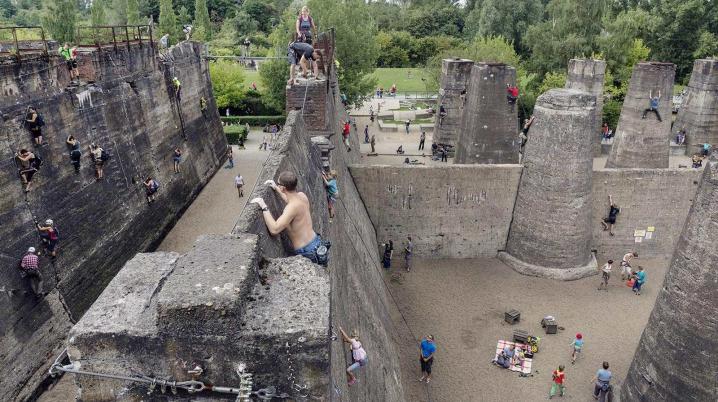 a man standing on the edge of a ruin in a park in Duisburg, Germany, looking down while other people are climbing the walls